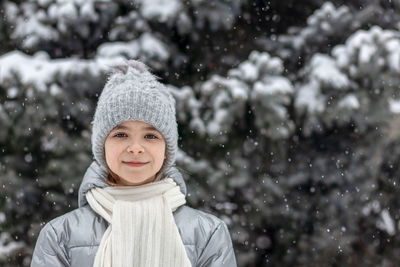 Portrait of a girl walking outdoors against the backdrop of a christmas tree in the snow. 