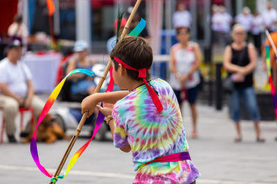 Rear view of woman playing with umbrella on street