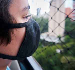 Brazilian boy using mask during the quarantine looking outside.
