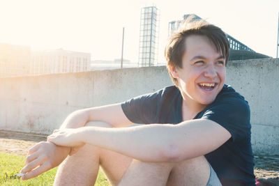 Smiling teenage boy sitting on field during sunny day