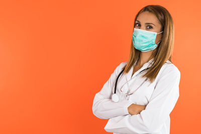 Portrait of female doctor standing against yellow background