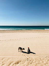 Man with umbrella on beach against clear sky