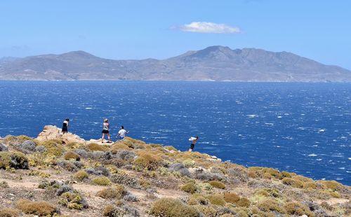 People standing on rock by sea against sky