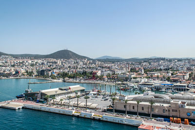 Illuminated city by sea against clear sky