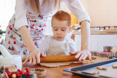 Midsection of mother teaching cooking to son