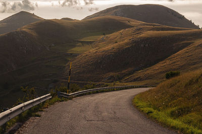 Empty road leading towards mountains against sky