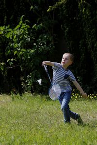 Full length of boy playing badminton in yard