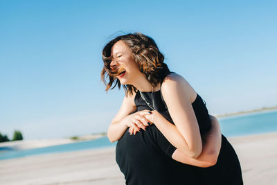 Woman standing at beach against sky