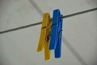 Close-up of clothespins hanging on rope against wall