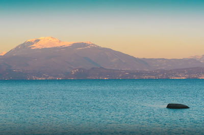 Scenic view of sea and mountains against sky during sunset