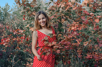 Portrait of young woman standing against plants