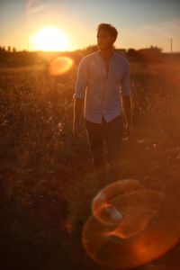 Man standing on field against sky during sunset