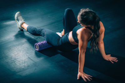 Woman using foam roller to self-massage muscles in the gym