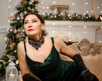 Portrait of young woman standing against christmas tree