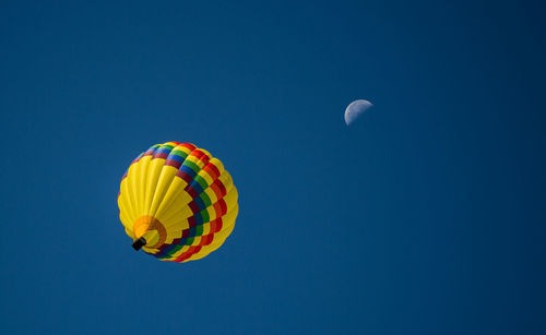 Low angle view of colorful hot air balloon flying against blue sky