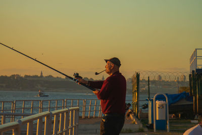 Rear view of man standing against sky during sunset