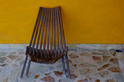 Close-up of empty chair against yellow wall