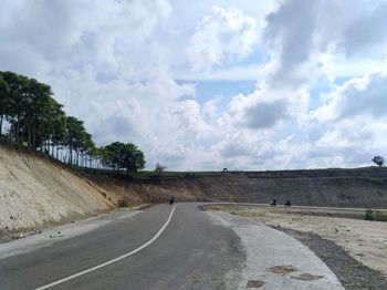 Empty road by landscape against sky