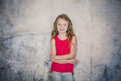 Portrait of smiling girl standing against textured wall