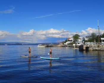 People on sea against blue sky