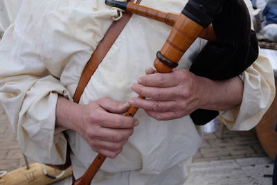 Midsection of male street artist playing bagpipe on footpath