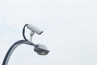 Low angle view of security camera on street light against clear sky