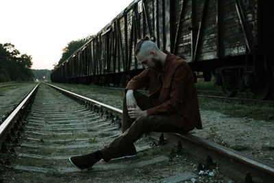 Side view of man sitting on railroad track