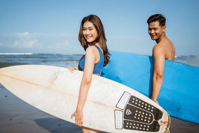 Portrait of smiling young woman sitting at beach