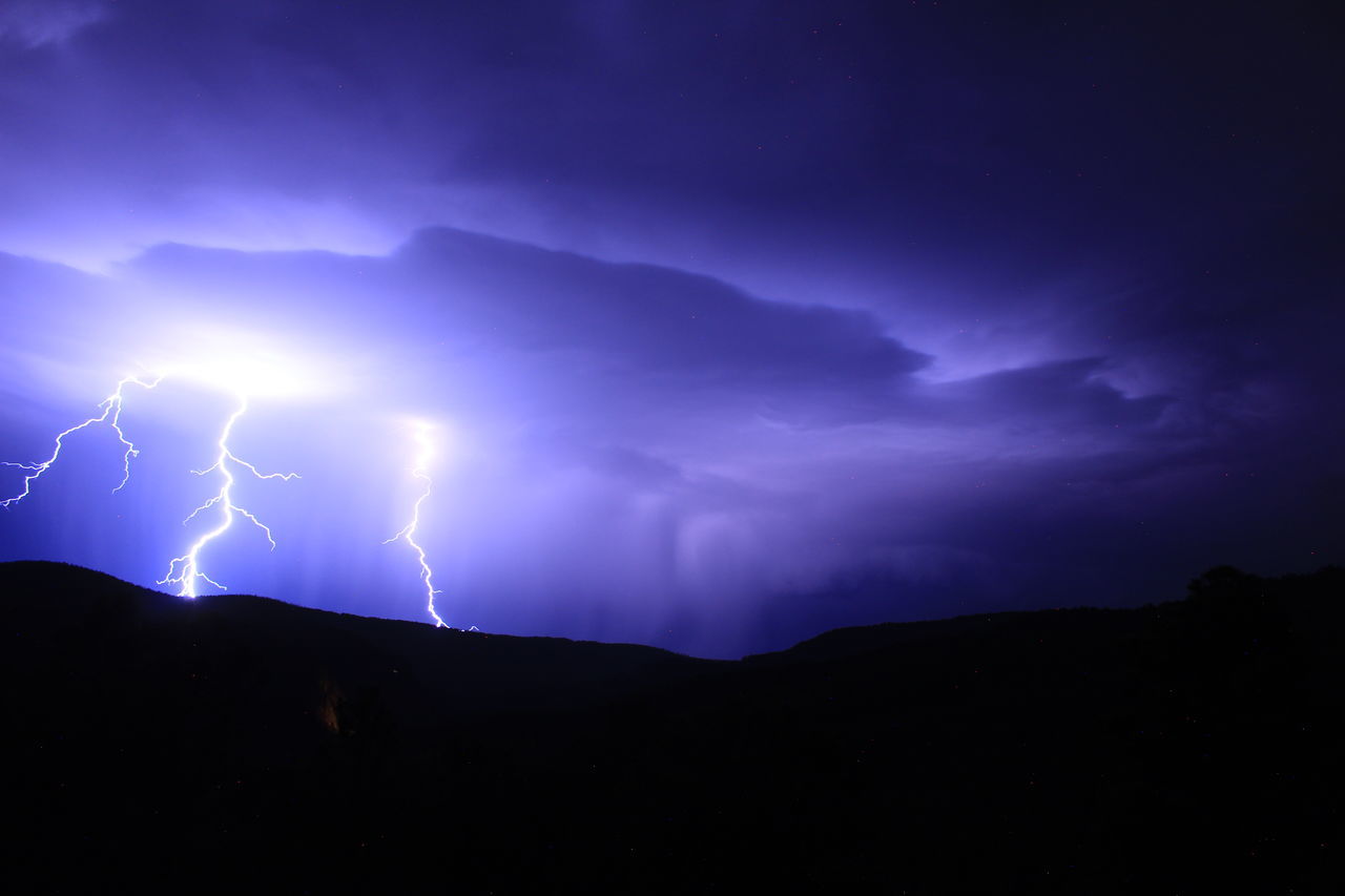 lightning, power in nature, storm, thunderstorm, cloud, beauty in nature, thunder, sky, warning sign, night, dramatic sky, forked lightning, environment, storm cloud, sign, communication, electricity, nature, no people, scenics - nature, bolt, outdoors, dark, extreme weather, mountain, silhouette, atmospheric mood, awe, overcast, landscape, illuminated, light - natural phenomenon, rain, meteorology, purple, darkness, wet