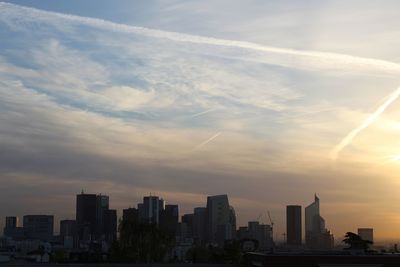 Modern buildings in city against sky during sunset