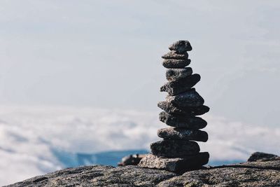 Stack of pebbles on rock against sky
