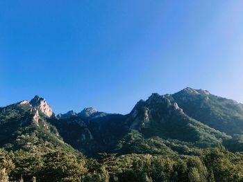 Low angle view of mountains against clear blue sky