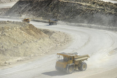 High angle view of construction vehicles moving on road by hill