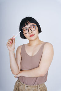 Young woman holding pen against white background