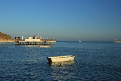 Boat sailing in sea against clear blue sky