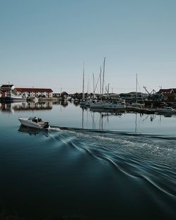 Sailboats in marina at harbor against clear sky