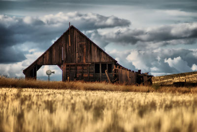 Abandoned barn on field against sky