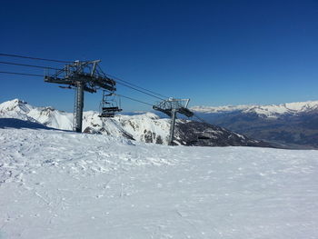 Snow covered landscape against clear blue sky