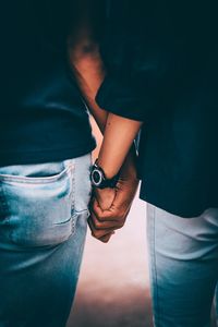 Midsection of couple holding hands outdoors