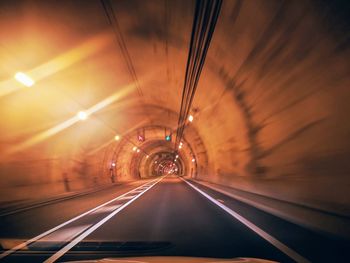 Road in illuminated tunnel seen through car windshield
