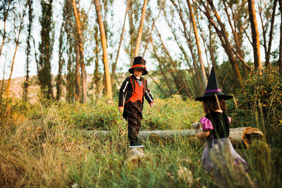 Rear view of boys standing on land in forest