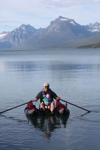 Men with boy in boat on river against mountain