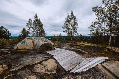 Abandoned wooden structure on field against sky