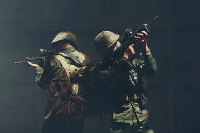 Close-up of soldiers with gun against black background