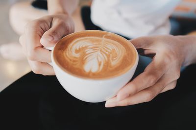 Midsection of man holding coffee cup