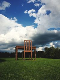 Empty chair on field against sky