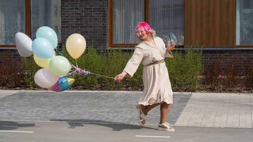 Full length of young woman holding balloons