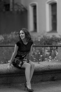 Portrait of young woman sitting on railing