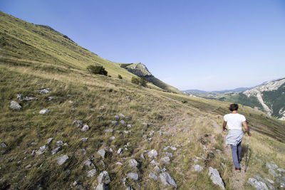 Rear view of man walking on mountain against sky