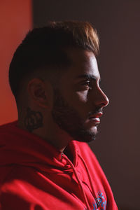 Close-up portrait of young man against red background